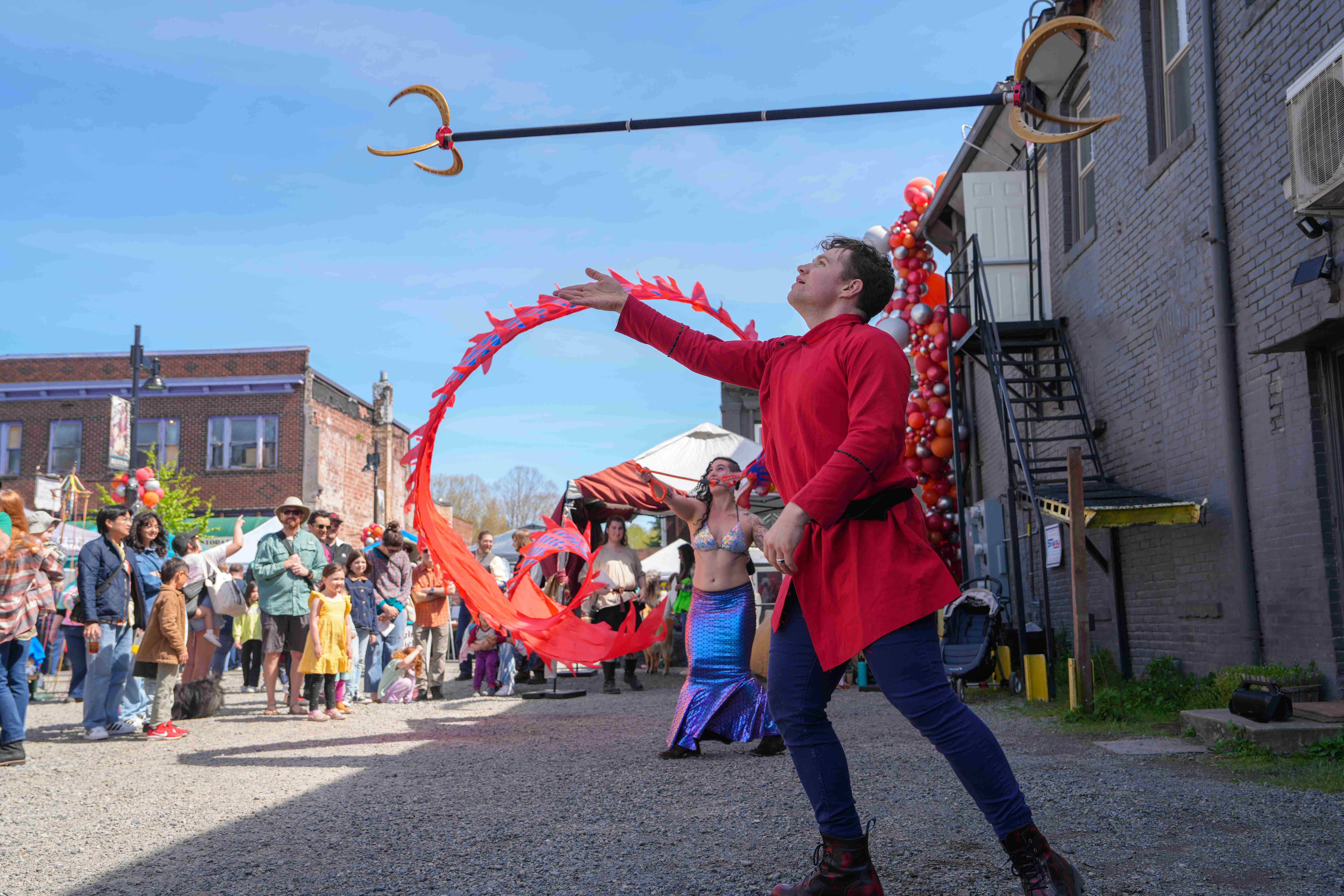 Man in red throwing pitchfork in air as entertainment during Dragons Landing Celebration