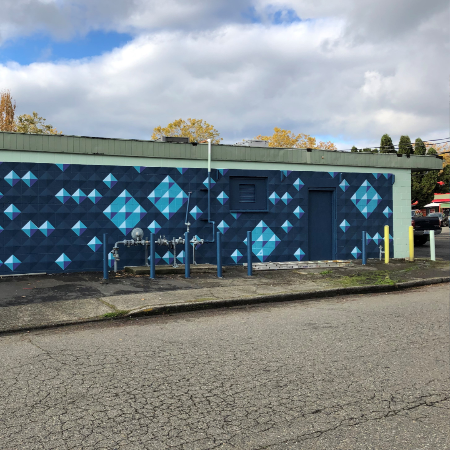 Mural of dark blue and light blue painted diamond shapes on a commercial building