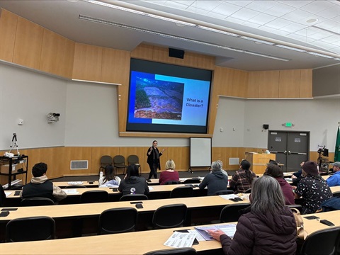 Classroom and instructor during preparedness class with Emergency Management with a screen that says what is a disaster?